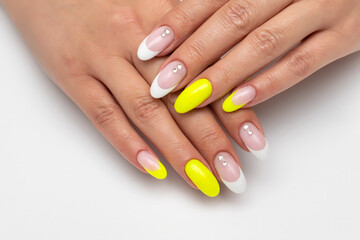 Gel bright yellow, white manicure with rhinestones, sparkles on long oval nails on a white...