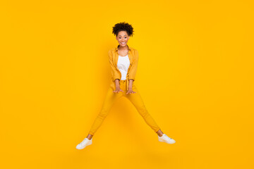 Fototapeta na wymiar Full length photo of young cheerful black girl have fun jump up fly air isolated over yellow color background
