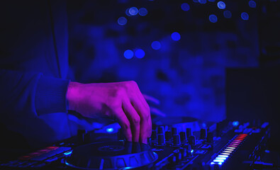 DJ Hands creating and regulating music on dj console mixer in concert nightclub