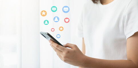 Young woman holding and using smartphone with icons of social media or notification icons.