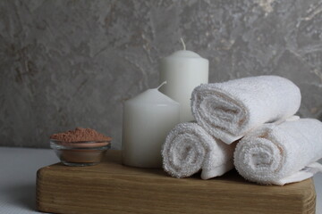 Obraz na płótnie Canvas spa treatments relax. Home body care. White towel candles salt for the bath lie on a wooden tray on a gray background