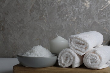 spa treatments relax. Home body care. White towel candles salt for the bath lie on a wooden tray on a gray background