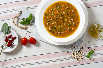 Italian minestrone soup with vegetables and beans on a table with a linen tablecloth