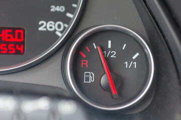 Fuel gauge with red indicator at empty level.Close-up car dash board petrol meter, fuel gauge, with...