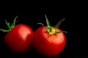 Two red cherry tomatoes on a black background, tomatoes with water droplets close-up view. Healthy eating concept photo