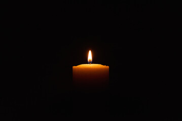One single light candle burning brightly in the black background.Spiritual candle yellow flame. Flame of candle in the darkness.Copy space.