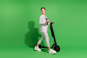 Photo of charming sweet woman dressed checkered clothes walking kick scooter looking empty space...