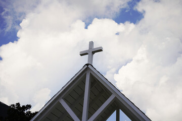 Cross with cumulus clouds in background.