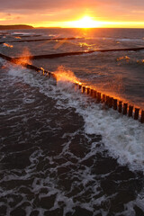 Beautiful sunset over the sea in stormy weather with red reflexes on the spray and sea foam