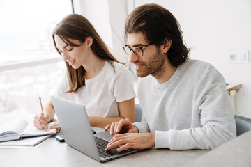 Young multiracial couple smiling while working with laptop together