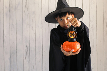 A boy with halloween costume and holding a lantern and pumpkin