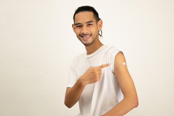 Happy Asian man showing his arm and bandage after they get a vaccine.