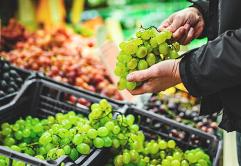 man hand holding grape in grocery store in supermarket