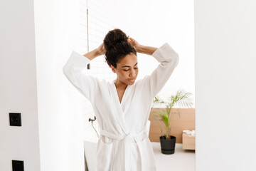 Black woman wearing bathrobe smiling while posing at home