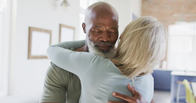 Mixed race senior couple hugging each other at home