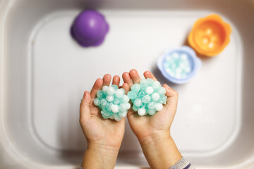 Baby play sensory hydrogel box, kids hands touch, play with blue water beads, sensory development and montessori, themed activities with children