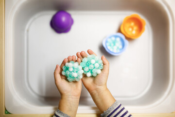 Baby play sensory hydrogel box, kids hands touch, play with blue water beads, sensory development and montessori, themed activities with children