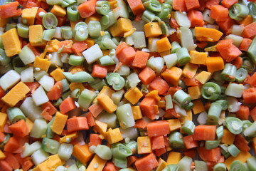 Vegetables, organic, cooked, cut very small, with carrots, pumpkin and chayote. Background and texture.