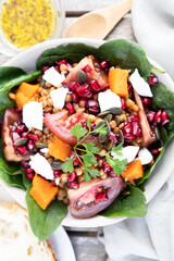 Lentil salad with pumpkin, tomatoes, pomegranate seeds, spinach and goat cheese. Refreshing legume and vegetable salad. Vegetarian food photography
