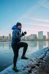 Fototapeta na wymiar A man is engaged in functional training in winter in very cold and clear weather. Running on the spot. on the background of the city