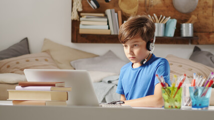 concentrated student boy studying on the computer at remote school on the web, concept of browsing and searching the internet or other activities such as social media or online games or entertainment