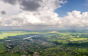 Bright landscape of white puffy cumulus clouds on blue clear sky over rural area.