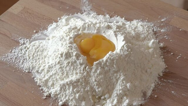 Putting an egg yolk onto a heap of wheat flour - preparation for baking cookies
