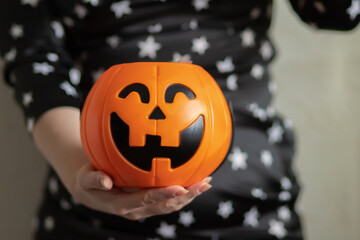 Halloween candy bowl pumpkin with lollipops in the hands of a woman on a holiday party