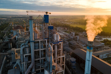 Aerial view of cement factory with high concrete plant structure and tower crane at industrial production area. Manufacture and global industry concept.