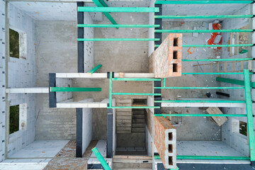 Aerial view of unfinished frame of private house with aerated lightweight concrete walls and wooden roof beams under construction.