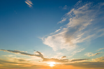 Bright colorful sunset sky with setting sun and vibrant clouds.