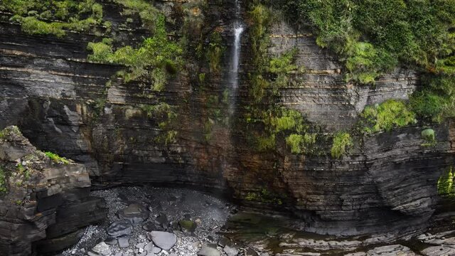 Waterfall spills down steep seacliffs on Basque Country coastline, Spain. High quality 4k footage