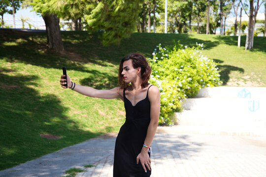 young latina and transsexual woman is taking a picture with her mobile phone. The woman is wearing a black dress. Concept diversity, transgender, and freedom of homosexual expression.