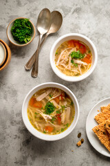 Chicken noodle soup, two bowls with vegetable broth, top view.