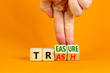 Trash to treasure symbol. Businessman turns cubes and changes the word trash to treasure. Beautiful orange table, orange background. Business, trash to treasure concept. Copy space.