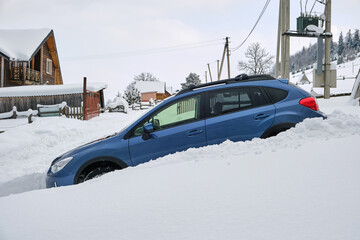 Car stuck in deep snow on cold winter day.
