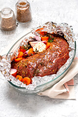Meat with vegetables is baked in foil. Raw beef, vegetables, spices and herbs are wrapped in foil. Cooking meat in the oven. Food for weekends and holidays. 