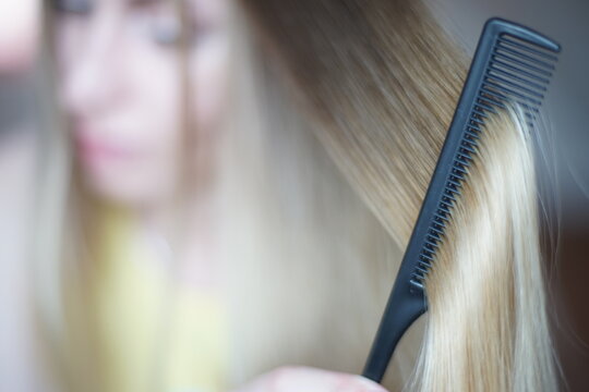 Young woman with a lock of shatush hair close up. The process of combining with a fine black comb.