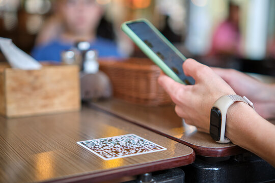 Closeup of guest hand ordering meal in restaurant while scanning qr code with mobile phone for online menu.