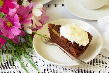 Chocolate plum cake with whipped cream, served with cocoa. Rustic style.
