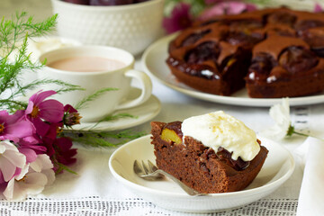 Chocolate plum cake with whipped cream, served with cocoa. Rustic style.