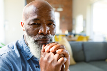 Portrait of thoughtful senior african american man in living room holding walking cane