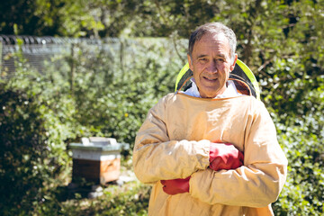Caucasian senior man wearing beekeeper uniform and looking at camera