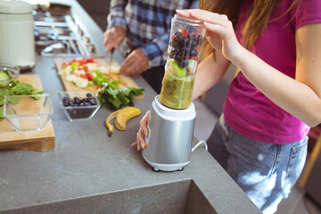 Midsection of caucasian grandfather and granddaughter preparing smoothie in kitchen
