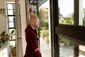 Thoughtful albino african american man with dreadlocks looking out the window