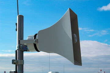 Loudspeaker of the emergency warning system against the background of a blue sky.