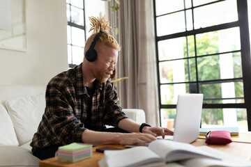 Albino african american man with dreadlocks working from home and making video call on the laptop