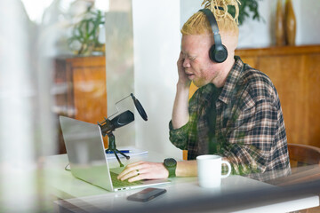 Albino african american man with dreadlocks working from home and making podcast