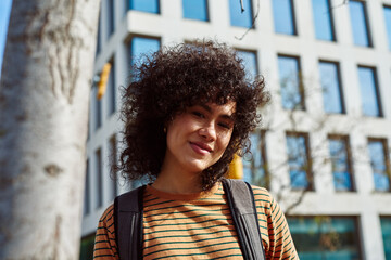 Happy young woman looking at camera in the city