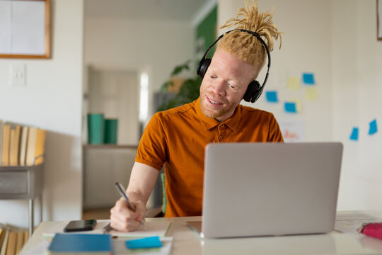 Albino african american man with dreadlocks working from home and making video call on the laptop